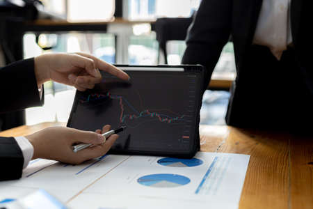 Two stock investors are brainstorming stock trading plans and reading stock market analysis, cryptocurrency investing, chart analysis and indicators to make profits in stocks. investment ideaの写真素材