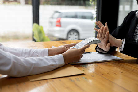 Business man raised her hand to deny accepting a bribe from a business partner, a brown envelope...