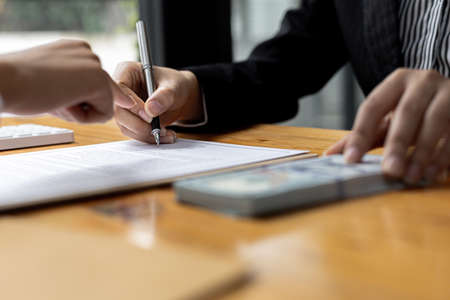 Two people are doing corrupt behavior, they are mutual business partners and are signing contracts to receive bribes for mutual benefit. The concept of business fraud and bribery is illegal.の写真素材