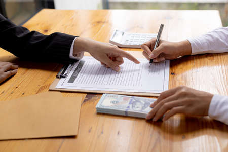 Two people are doing corrupt behavior, they are mutual business partners and are signing contracts to receive bribes for mutual benefit. The concept of business fraud and bribery is illegal.の写真素材