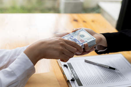 Two people are doing corrupt behavior, they are mutual business partners and are signing contracts to receive bribes for mutual benefit. The concept of business fraud and bribery is illegal.の写真素材