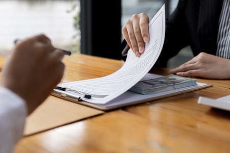 Two people are doing corrupt behavior, they are mutual business partners and are signing contracts to receive bribes for mutual benefit. The concept of business fraud and bribery is illegal.の写真素材