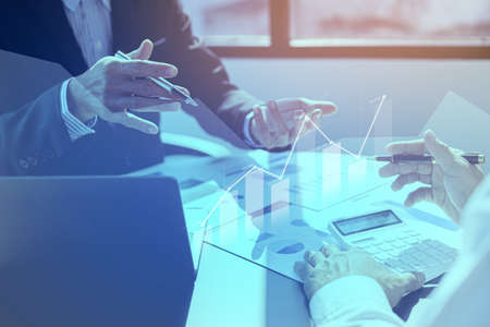 Two businessmen are meeting together, they point to financial documents to discuss plans and solutions, chart graphics showing financial status and performance. Business administration concept.の写真素材