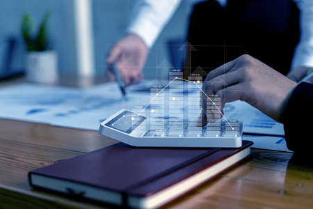 Two businessmen are meeting together, they point to financial documents to discuss plans and solutions, chart graphics showing financial status and performance. Business administration concept.の写真素材