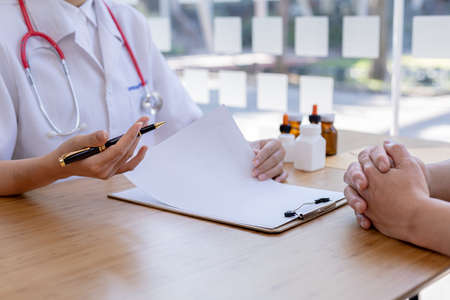 An examination room atmosphere in a hospital where doctors and patients are examining and diagnosing and prescribing medications for symptomatic treatment. The concept of disease diagnosis.の写真素材
