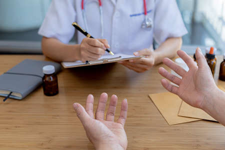 An examination room atmosphere in a hospital where doctors and patients are examining and diagnosing and prescribing medications for symptomatic treatment. The concept of disease diagnosis.の写真素材