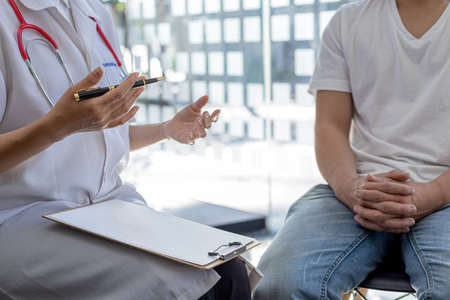 An examination room atmosphere in a hospital where doctors and patients are examining and diagnosing and prescribing medications for symptomatic treatment. The concept of disease diagnosis.の写真素材