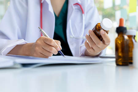 The pharmacist is reviewing the list of drugs and checking the stock of all medicines at one of the...