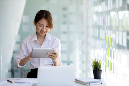 young businesswoman looking at financial information from a tablet, she is checking company financial documents, she is a female executive of a startup company. Concept of financial management.