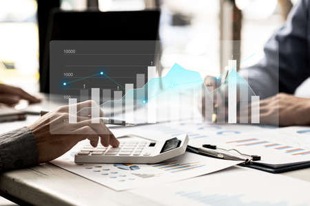 Two businessmen are meeting together, they point to financial documents to discuss plans and...