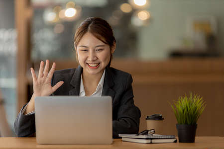 Beautiful Asian businesswoman sitting in her private office, she is talking to her partner via video...