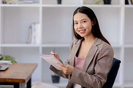 Beautiful Asian woman is a businesswoman who leads a new generation of startups, a woman who runs and manages a business plan to build confidence and stability in business, woman-led business concept.の写真素材