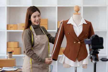 A beautiful Asian woman who owns a clothing brand, she is live chatting with customers and...