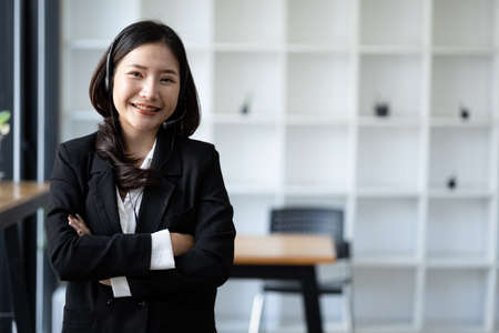 Beautiful Asian woman, she is a call center employee of an Internet and telephone company, she is responsible for providing service and assistance to customers through the phone. Call center concept.の写真素材
