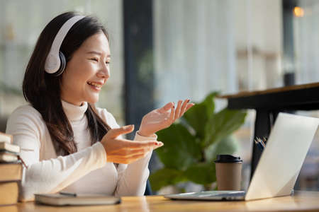 Beautiful Asian woman presenting work in class to teacher and friend, she is studying online. The...