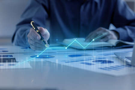A business man examines data on financial documents, company financial reports, graphics showing financial and numerical growth data. The concept of financial management to grow and be profitable.の写真素材