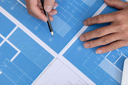 Architect pointing to building plans for review and editing, architect engineers design houses and interior structures and draw plans through design program. Architect concept of building design.の写真素材