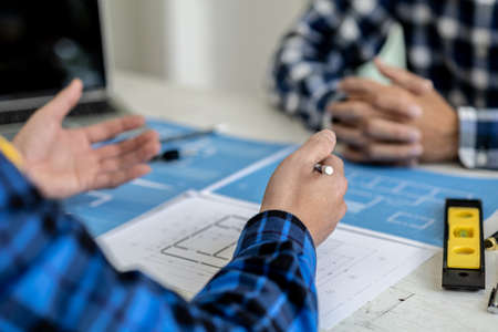 Two people are discussing the design of the building plan, the architect engineer designs the house...