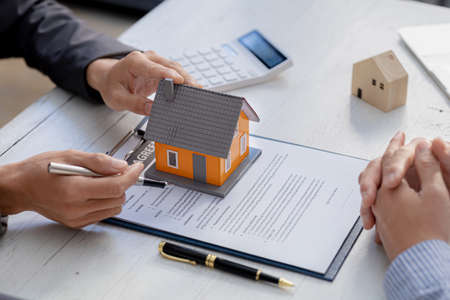 Rental company employee is discussing the details before the customer agrees to sign a rental contract, explaining the details and the terms and conditions of the rental. Real estate rental ideas.の写真素材