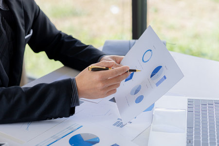 A business finance woman is reviewing a company's financial documents prepared by the Finance Department for a meeting with business partners. Concept of validating the accuracy of financial numbers.の写真素材