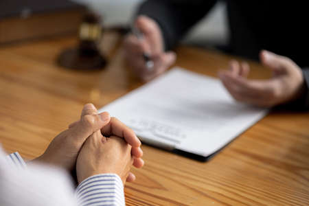 Client was listening to a lawyer advising on an embezzlement case, explaining the details of the proceeding and gathering evidence to file a lawsuit against the defendant. The concept of litigation.の写真素材