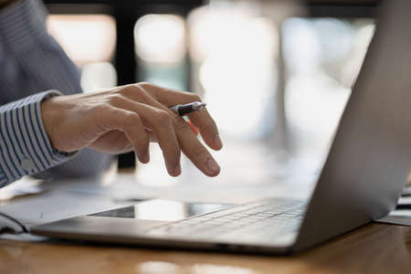 A business man is checking company financial documents and using a laptop to talk to the chief financial officer through a messaging program. Concept of company financial management.の写真素材