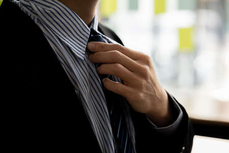 Close-up of a business man holding a necktie for a smart and polite dress before going into business with customers. The concept of formal and courteous clothing for business dealings.の写真素材