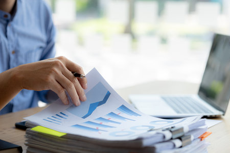 Business man pointing to a chart document showing company financial information, He sits in a...
