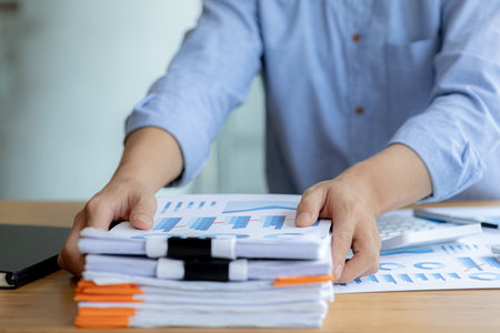 The office worker is working at the company, he is tidying up the paperwork on his desk to start...
