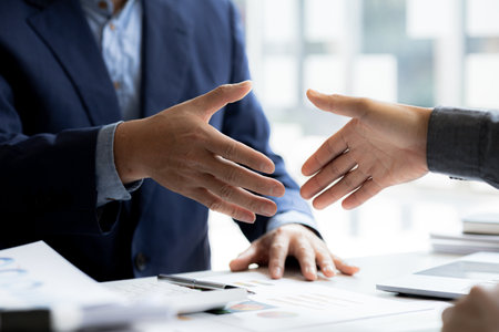 Close-up two business men holding hands, Two businessmen are agreeing on business together and shaking hands after a successful negotiation. Handshaking is a Western greeting or congratulation.の写真素材