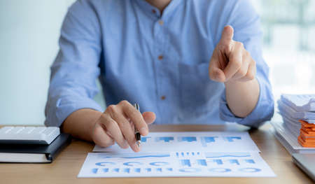 Business man pointing to a chart document showing company financial information, He sits in a...