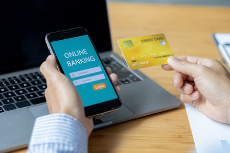 A person is holding a credit card to pay online, credit card payments can be used on both laptop computers and mobile phones. Concept of payment for goods and services via credit card.の写真素材