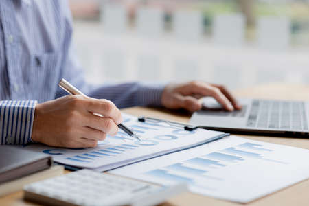 Businessman check to financial documents, he owns a startup company, he sits checking the company's financial summary prepared by the finance department. Management concept of startup company.の写真素材