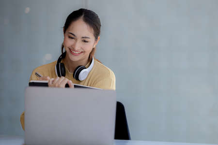 Beautiful Asian woman using a laptop to study online, she is studying online. The concept of online learning due to the COVID-19 outbreak to prevent an outbreak in the classroom.の写真素材