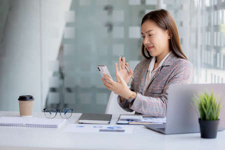 Beautiful Asian businesswoman sitting in a private office, she is talking to her partner via video...