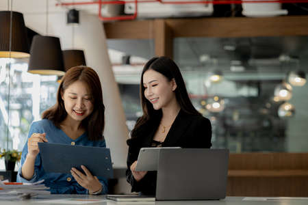 Atmosphere in the office of a startup company, two female employees are discussing, brainstorming...
