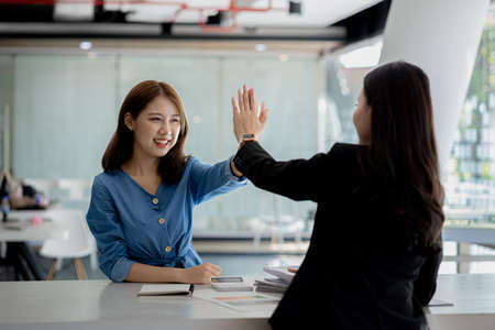 Two women showing joy and looking at data on their laptop, two business women looking at a monthly summary of sales that exceeded sales targets and achieved profitable growth. Sales management conceptの写真素材