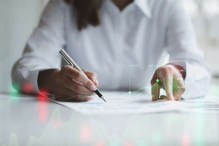 A business woman examines data on financial documents, company financial reports, graphics showing...