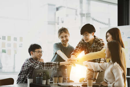 A group of young Asians are brainstorming and planning to run a growing startup business, working...