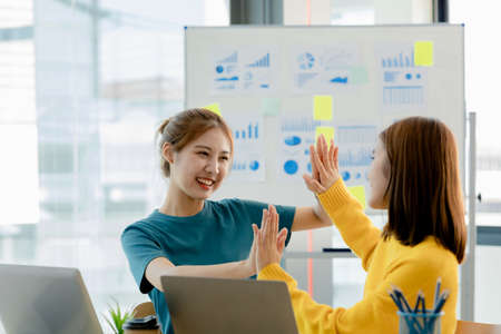Two women showing joy and looking at data on their laptop, two business women looking at a monthly summary of sales that exceeded sales targets and achieved profitable growth. Sales management conceptの写真素材