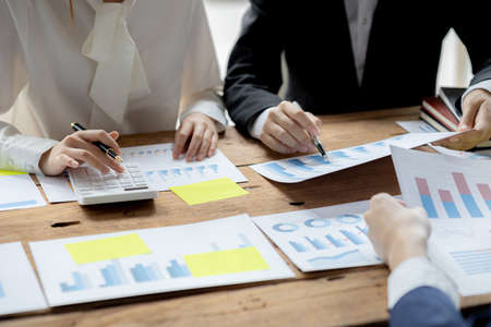 A desk in a company conference room has a group of business people attending and with supporting documents laid out, brainstorming sessions to fix and plan the company's growth. Business meeting idea.の写真素材