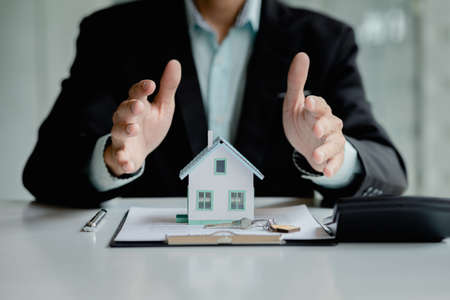 Person covers the model with his hand, Insurance house, and family health live concept. The insurance agent presents the hands protection model that symbolize the coverage.の写真素材