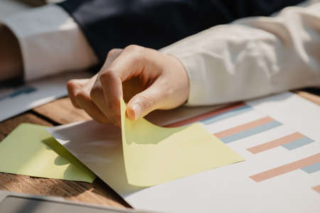 Businesswoman holding a notepad at her desk, a group of businessmen attending a meeting and holding...