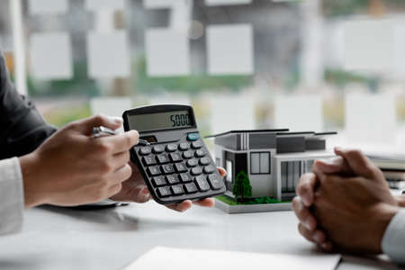 A rental company employee is calculating the cost for the customer to agree to sign a rental contract, explaining the rental terms and conditions. Home and real estate rental ideas.の写真素材