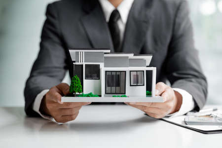 Real estate agents are holding a housing model of the project. Real estate trading ideas and bank loans for buying and selling houses and land.の写真素材