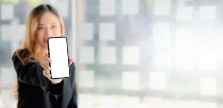 Asian woman holding white blank screen phone standing forward, smartphone blank screen for...