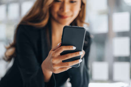 Young businesswoman looking at financial information from a mobile phone, she is checking company...