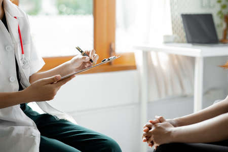An examination room atmosphere in a hospital where doctors and patients are examining and diagnosing and prescribing medications for symptomatic treatment. The concept of disease diagnosis.の写真素材