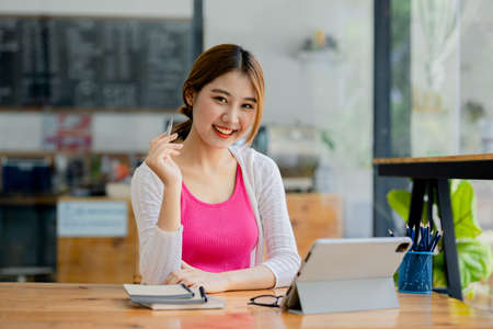 Beautiful Asian woman using a laptop to study online, she is studying online. The concept of online learning due to the COVID-19 outbreak to prevent an outbreak in the classroom.の写真素材