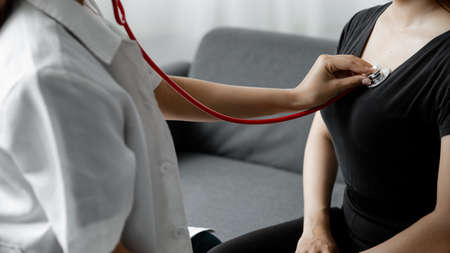 A female doctor using a stethoscope, she is examining the patient in the examination room and...